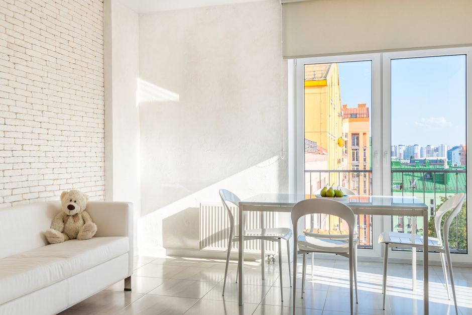 Two professional cleaners from Carpet Cleaners Bermondsey are performing sofa surface cleaning in a residential flat on Jamaica Road, Bermondsey. One cleaner with long dark hair is kneeling on the flo